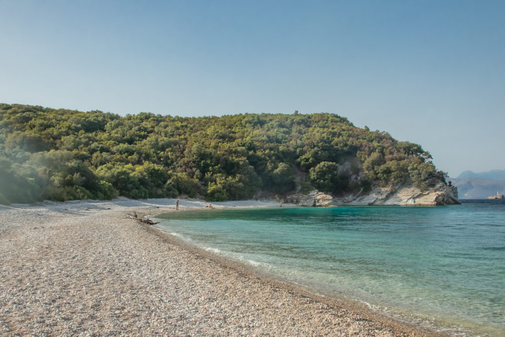 the best things to do in Corfu: secluded akoli beach with greenery and blue water